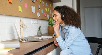 Happy african american teen girl student worker wear headphones video conference calling online on laptop computer laughing at home office.
