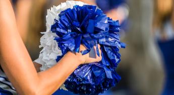 Cheerleader holding pom poms with a shallow depth of field
