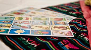an elegant table adorned with a Mexican handicraft tablecloth, on this a fun typical Mexican game called loteria, with different numbered figures even without the sheets being distributed to start the