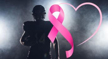 silhouette of football player behind pink breast cancer ribbon and heart