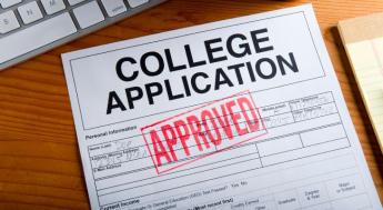 college application with approved stamp next to keyboard