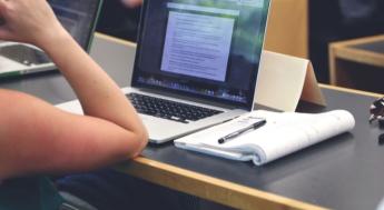 laptop computer open and student taking notes