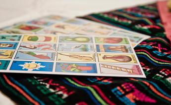 an elegant table adorned with a Mexican handicraft tablecloth, on this a fun typical Mexican game called loteria, with different numbered figures even without the sheets being distributed to start the