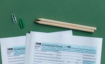 IRS tax forms on green background with two pencils and paperclips