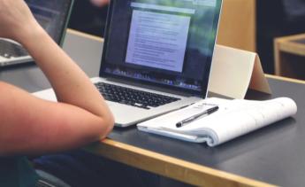 laptop computer open and student taking notes