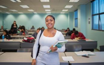 Student Standing in Classroom with Books