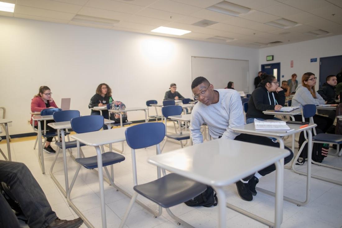 Student in the Classroom Searching in his Backpack