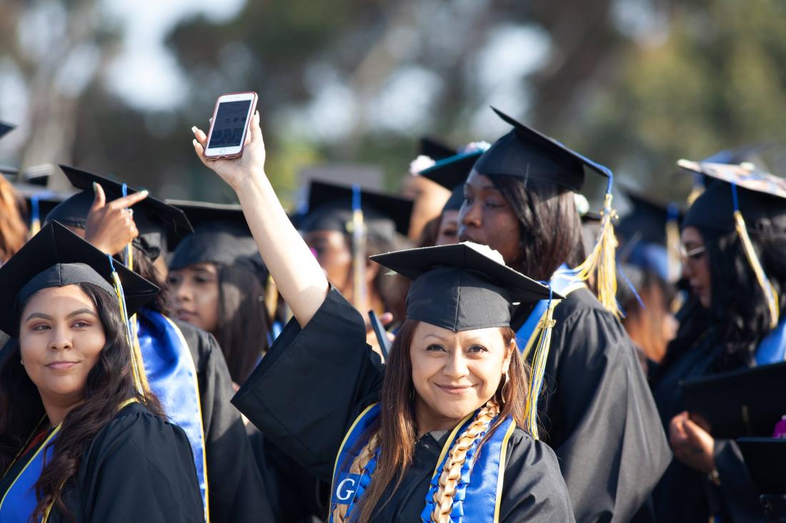 Student at Graduation Raising her Phone
