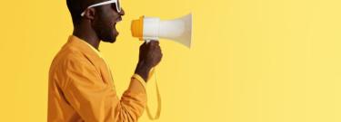 side profile of man wearing yellow speaking into megaphone