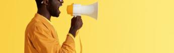 side profile of man wearing yellow speaking into megaphone