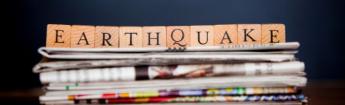 blocks spelling out earthquake on top of a stack of newspapers